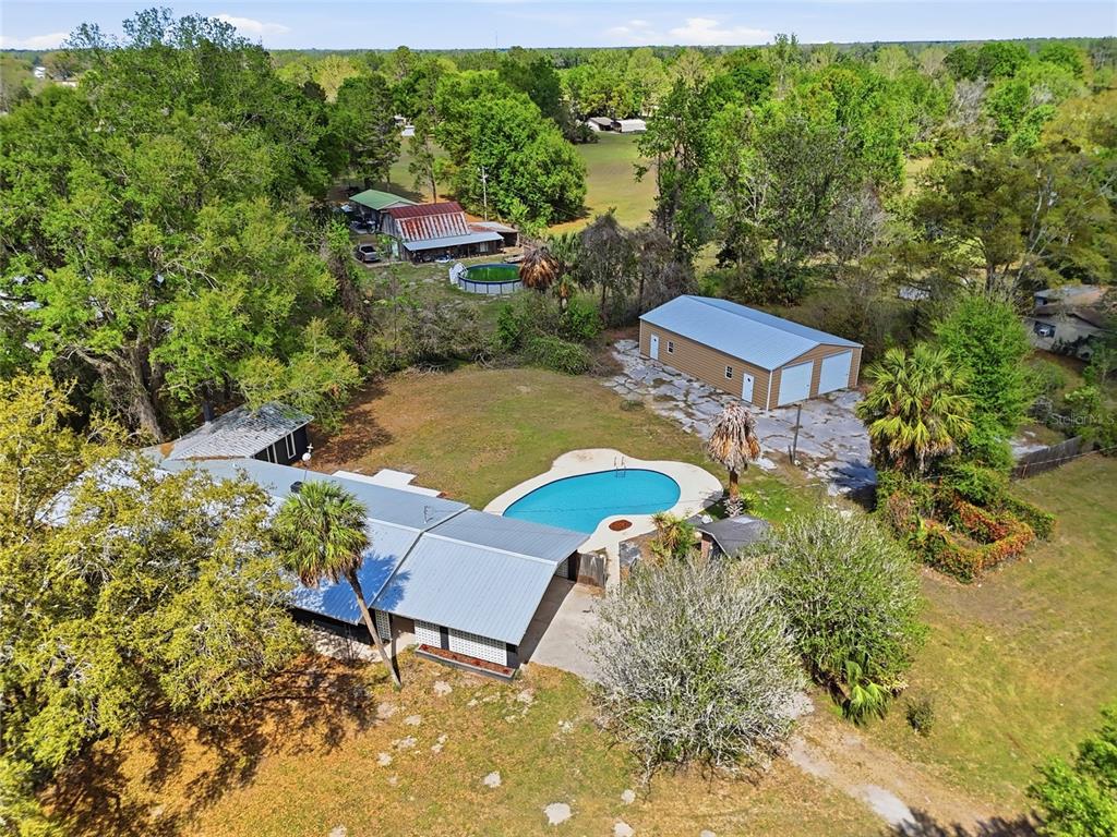 An aerial view shows a house with a pool, a detached garage, and surrounding trees — 980 SW 105TH STREET, TRENTON, FL