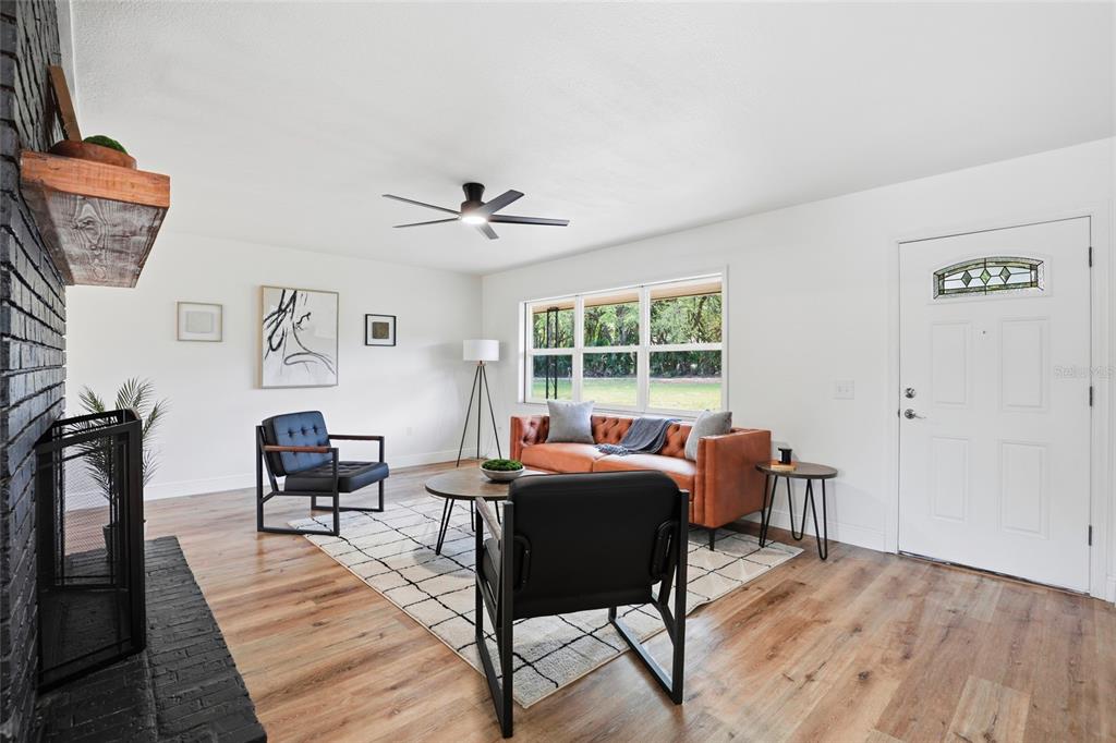 A living room features a black brick fireplace, wood flooring, and a leather sofa — 980 SW 105TH STREET, TRENTON, FL
