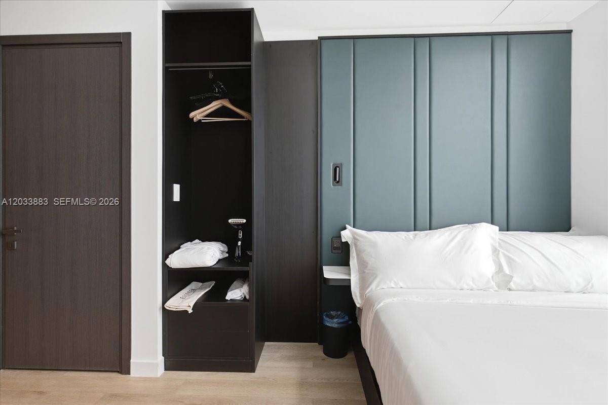 A bedroom features a dark wood wardrobe next to a bed with a teal headboard — 20 NE 11th # 4212, Miami FL 33132, MIAMI, FL