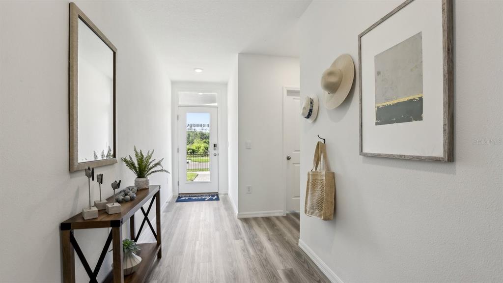 A bright entryway features light wood-look flooring, a console table, and a glass-paneled front door — 32387 WEATHERED OAK DRIVE, WESLEY CHAPEL, FL