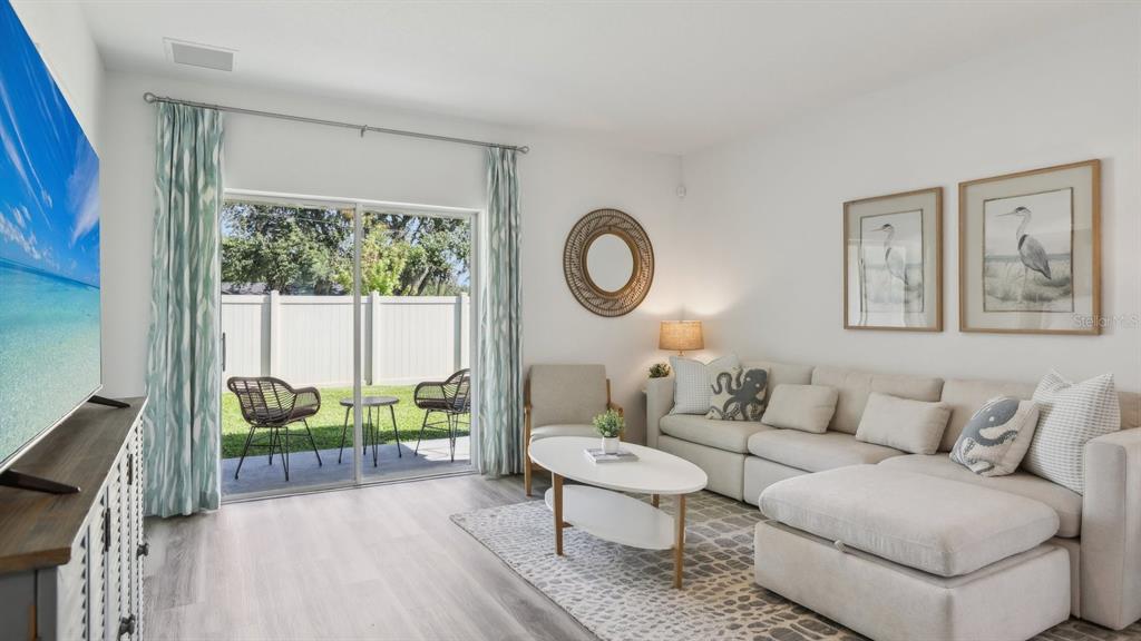 A living room features a sectional sofa, a coffee table, and sliding doors to a patio — 32387 WEATHERED OAK DRIVE, WESLEY CHAPEL, FL