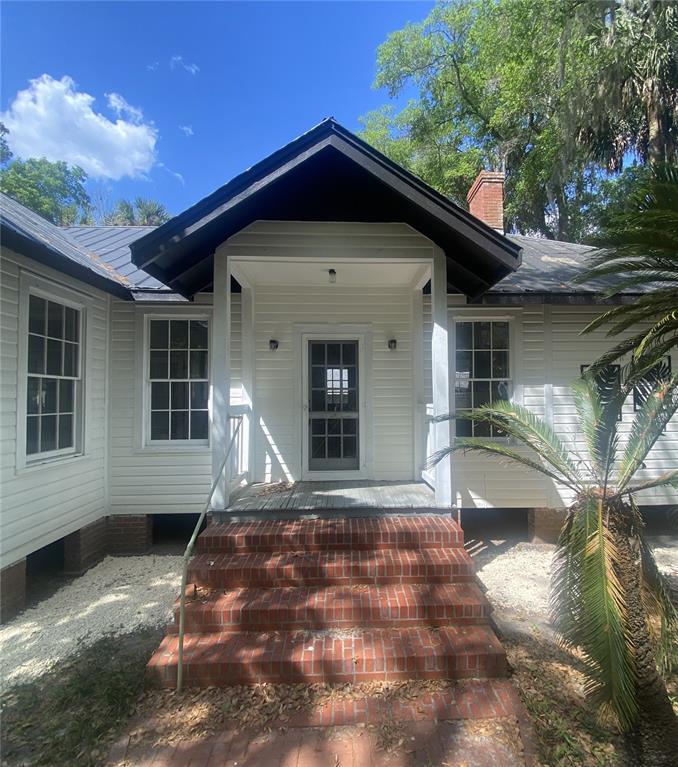 A white house with a gabled porch entrance, brick steps, and a metal roof — 6015 QUAIL STREET, MELROSE, FL