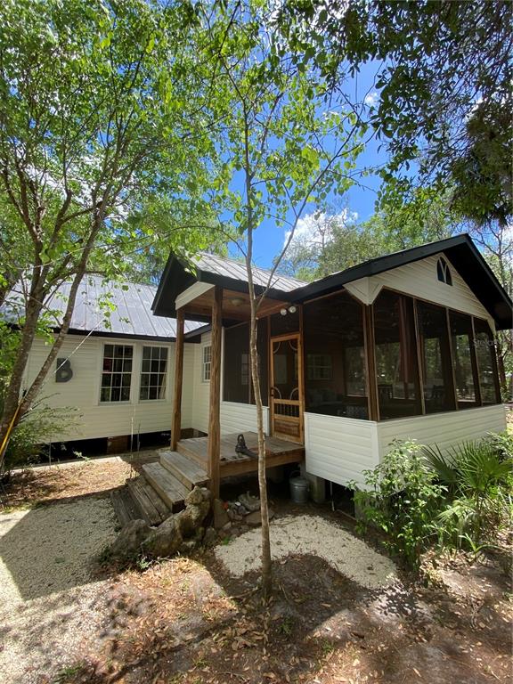 A white cottage with a screened-in porch and a metal roof sits among trees — 6015 QUAIL STREET, MELROSE, FL
