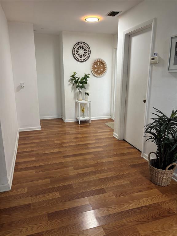 A living room features wood-look flooring, a television, and two tan reclining chairs — 1706 MARGATE BOULEVARD, LEHIGH ACRES, FL