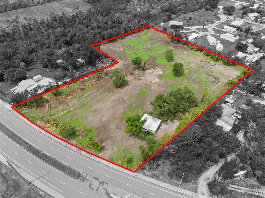 An aerial view shows a large, cleared rectangular lot with a small building and trees — 5230 PLACIDA ROAD, ENGLEWOOD, FL