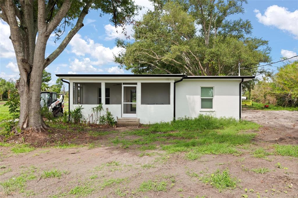 A white, single-story house with a screened-in porch and a large tree in the yard — 5230 PLACIDA ROAD, ENGLEWOOD, FL