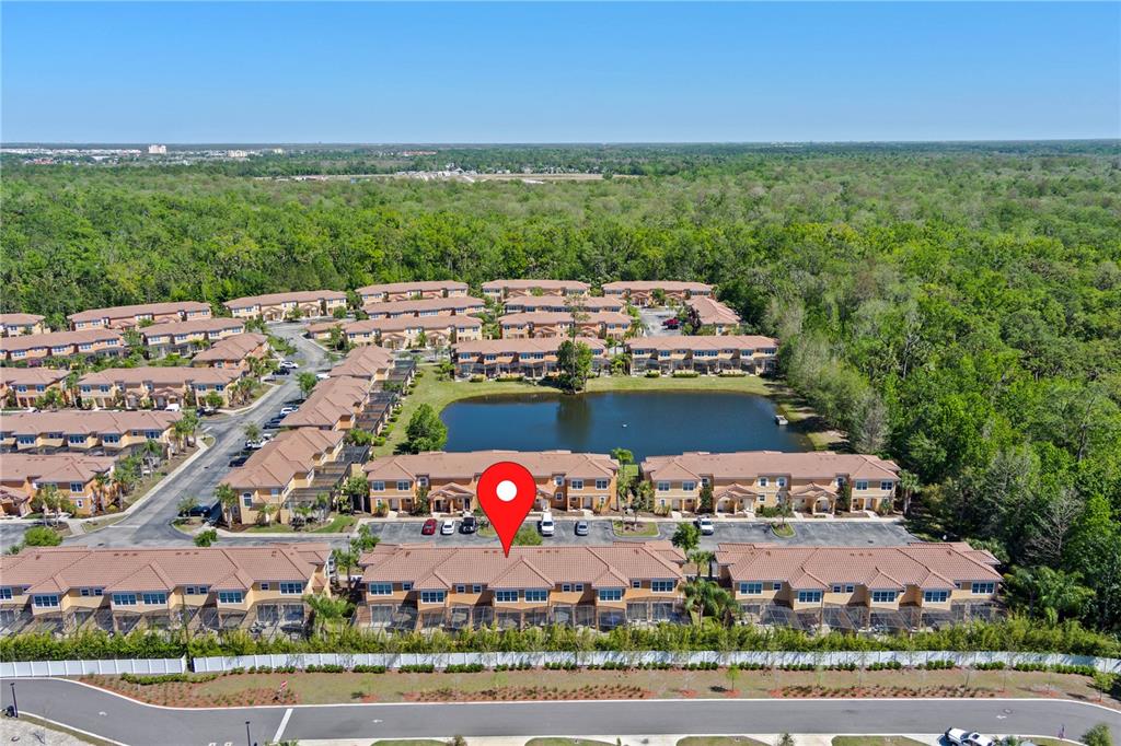 An aerial view shows a residential complex with townhouses surrounding a central pond — 2618 ROADSTER LANE, KISSIMMEE, FL