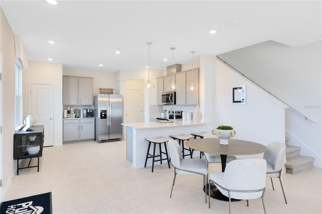 A modern kitchen with light gray cabinets, stainless steel appliances, and a dining area — 4401 JETTY LANE NE, PALM BAY, FL