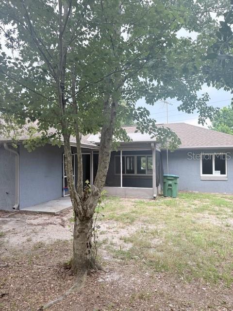 The exterior of a gray house features a screened-in porch and a large tree — 1717 PROVIDENCE BOULEVARD, DELTONA, FL