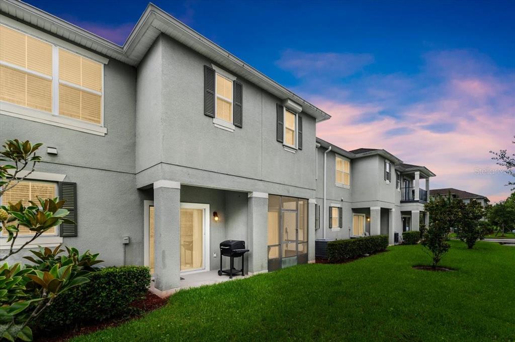 A two-story gray stucco townhouse with a screened-in patio and a grassy backyard — 107 WENTWORTH GRANDE DRIVE, DAYTONA BEACH, FL