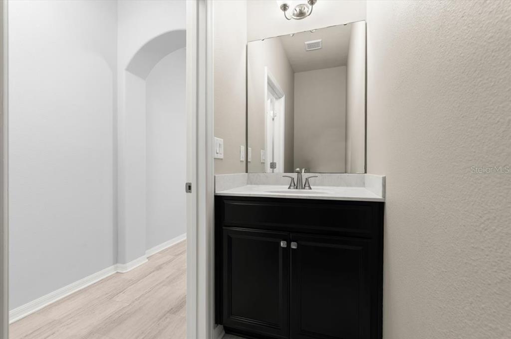 A bathroom features a dark wood vanity with a white countertop and a wall mirror — 107 WENTWORTH GRANDE DRIVE, DAYTONA BEACH, FL