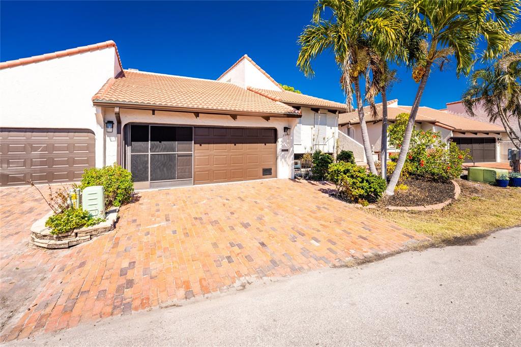 A single-story house with a brick driveway, a brown garage door, and palm trees — 25188 MARION AVENUE UNIT 21, PUNTA GORDA, FL