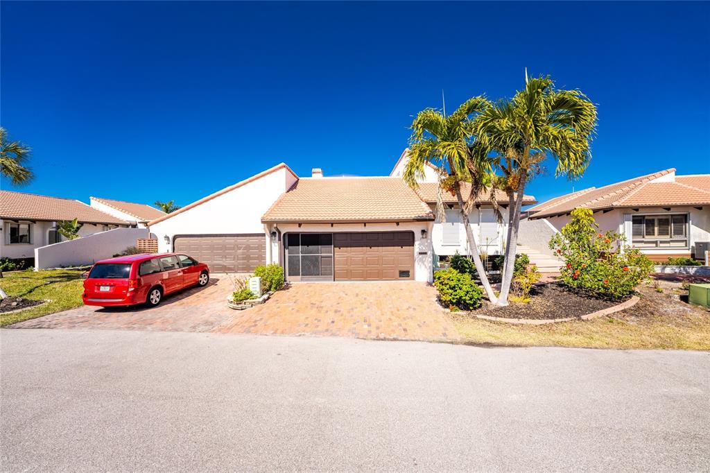 A single-story house with a two-car garage, a red minivan, and palm trees outside — 25188 MARION AVENUE UNIT 21, PUNTA GORDA, FL