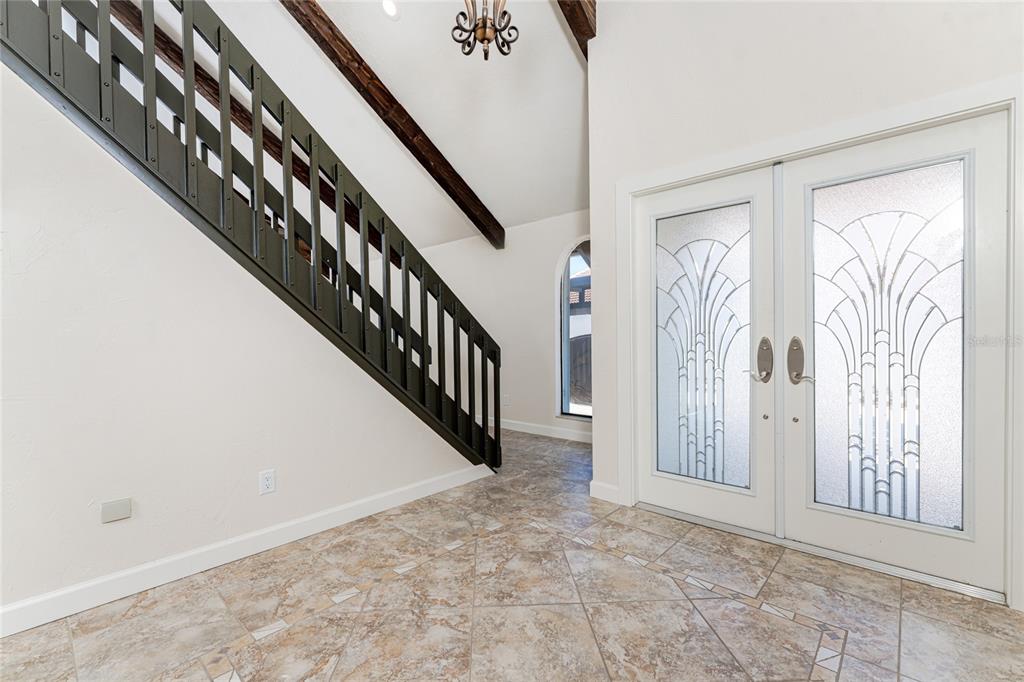 An entryway features a tiled floor, a dark metal staircase railing, and double glass doors — 25188 MARION AVENUE UNIT 21, PUNTA GORDA, FL