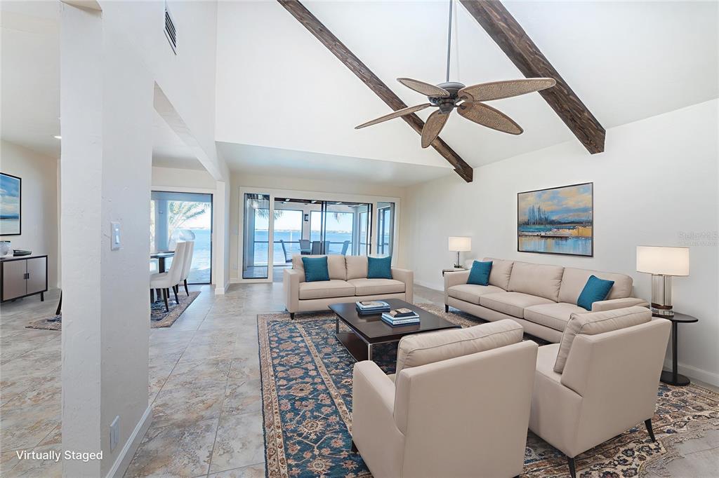 A living room with vaulted ceilings, exposed beams, tile floors, and a view of water — 25188 MARION AVENUE UNIT 21, PUNTA GORDA, FL