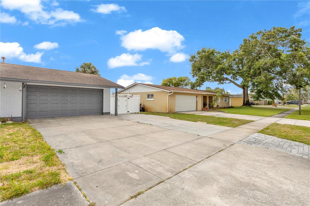 A view of two adjacent single-story houses with concrete driveways and a large tree — 5195 SHARLENE DRIVE, TITUSVILLE, FL