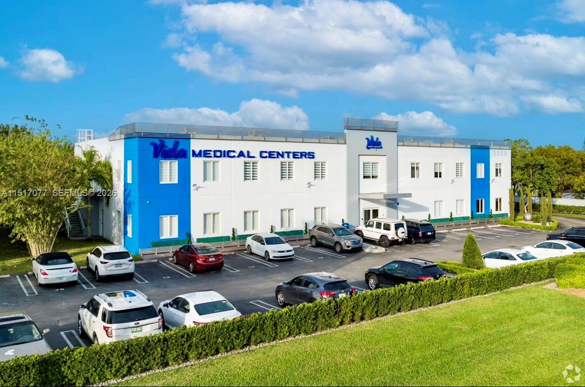 An exterior view of a two-story medical center building with a parking lot in front — 2550 NW 100th Ave, Doral FL 33172, DORAL, FL