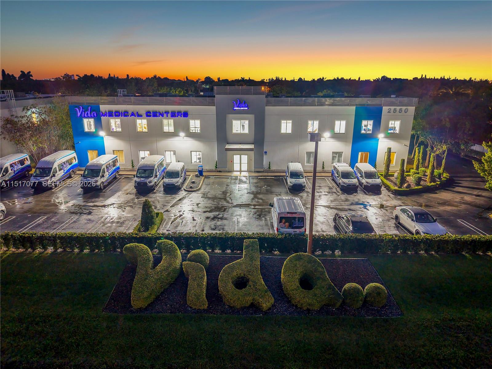 An aerial view of a two-story medical center building with a parking lot and topiary — 2550 NW 100th Ave, Doral FL 33172, DORAL, FL
