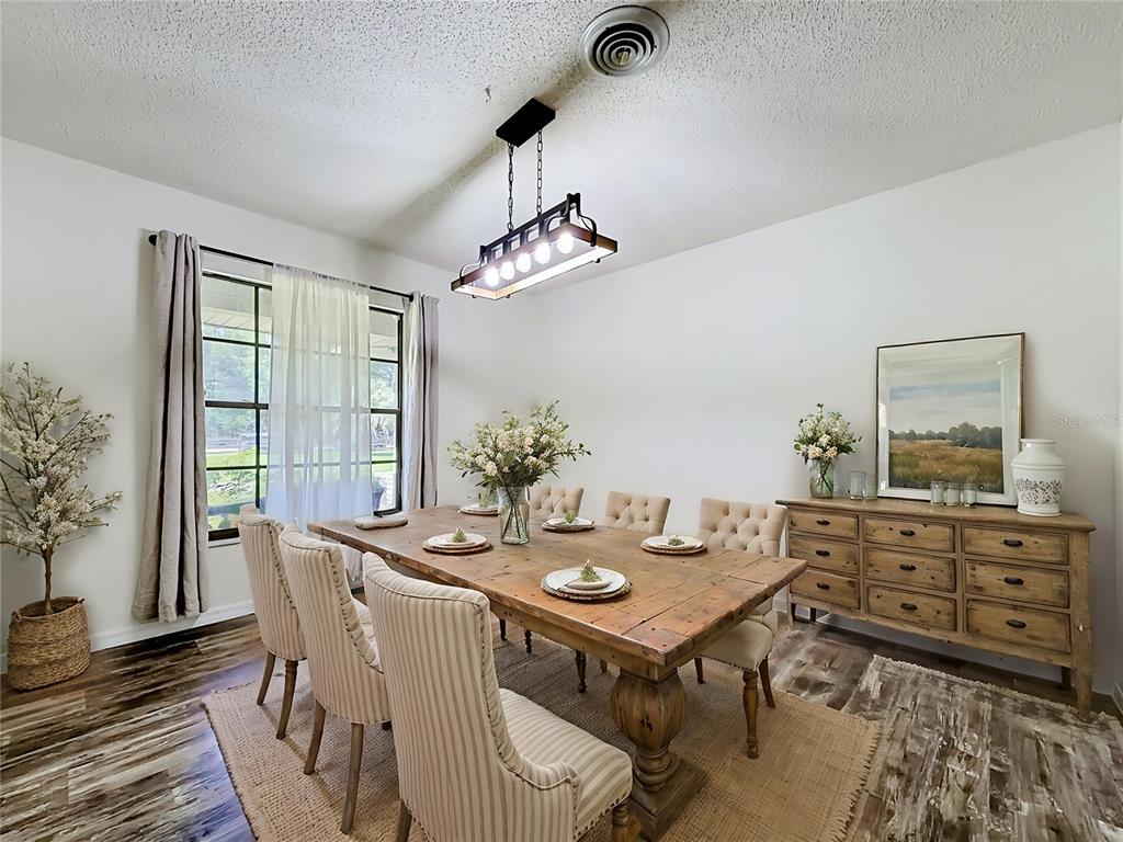 A dining room features a rustic wooden table, upholstered chairs, and a rectangular pendant light — 900 NE 165TH STREET, CITRA, FL