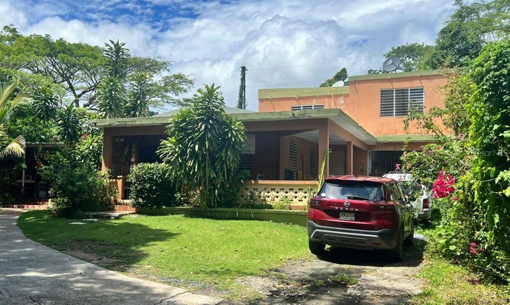 A two-story peach-colored house with a covered front porch and a red SUV parked outside — 12 Carr 993 DESTINO, VIEQUES, PR