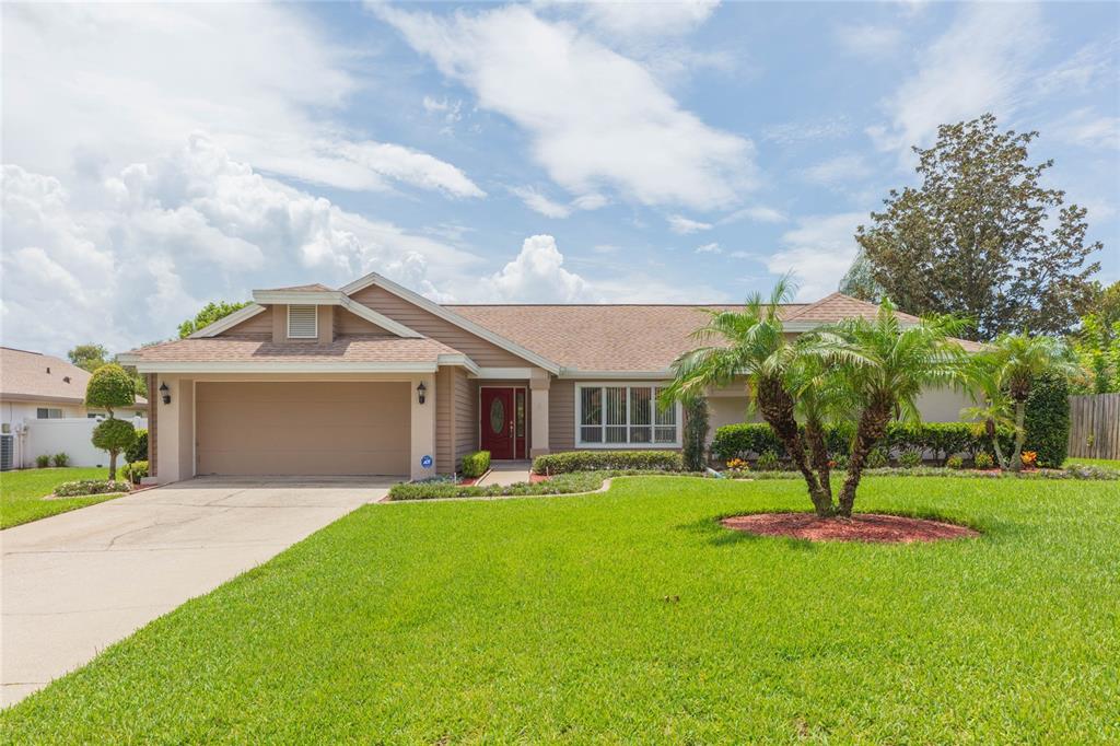 A single-story house with a tan exterior, a two-car garage, and a palm tree out front — 1405 OXFORDSHIRE COURT, BRANDON, FL