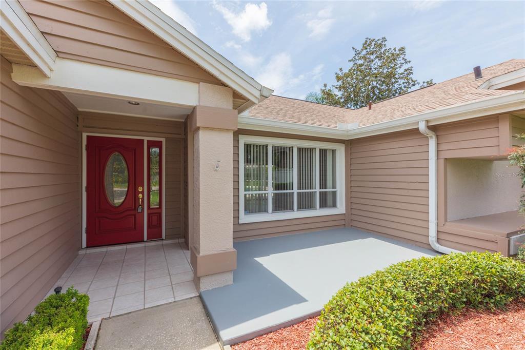 The exterior of a house features a red front door, a porch, and tan siding — 1405 OXFORDSHIRE COURT, BRANDON, FL