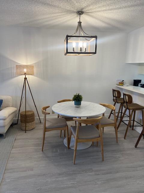 A dining area features a marble-topped table, wooden chairs, and a modern metal pendant light — 353 S Us Highway 1 # A107, Jupiter FL 33477, JUPITER, FL