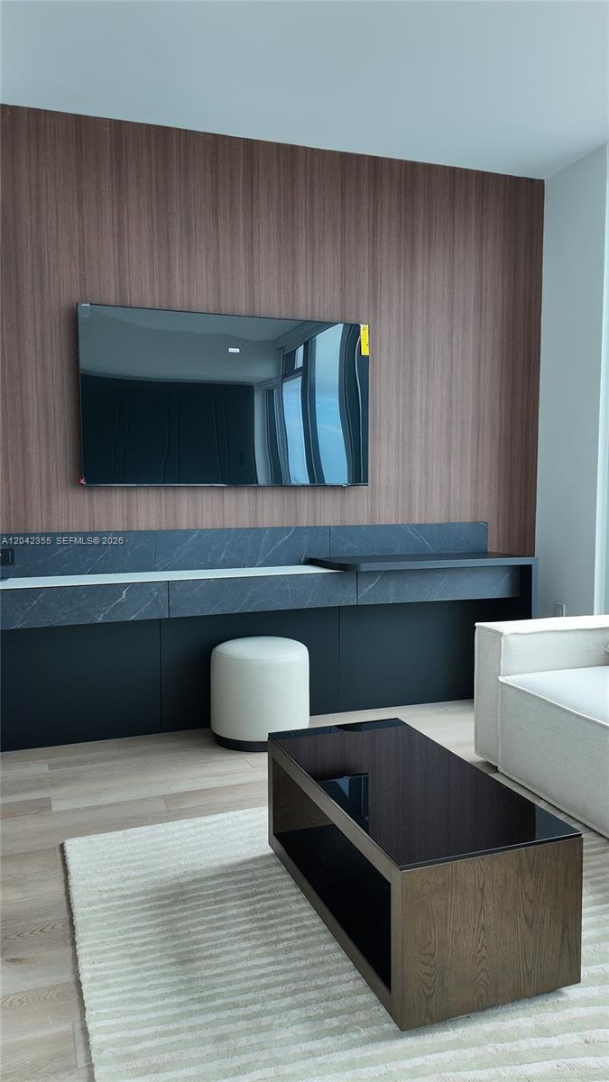 A living room features a wall-mounted television, a dark stone console, and a coffee table — 20 NE 11th St, Miami FL 33132, MIAMI, FL