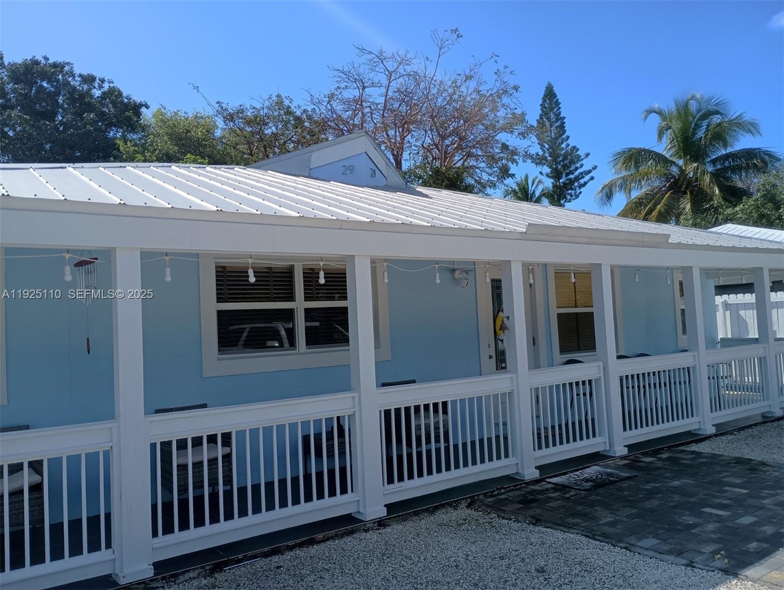 A light blue house features a white metal roof and a covered front porch railing — 29 Bonefish Ave, Key Largo FL 33037, KEY LARGO, FL