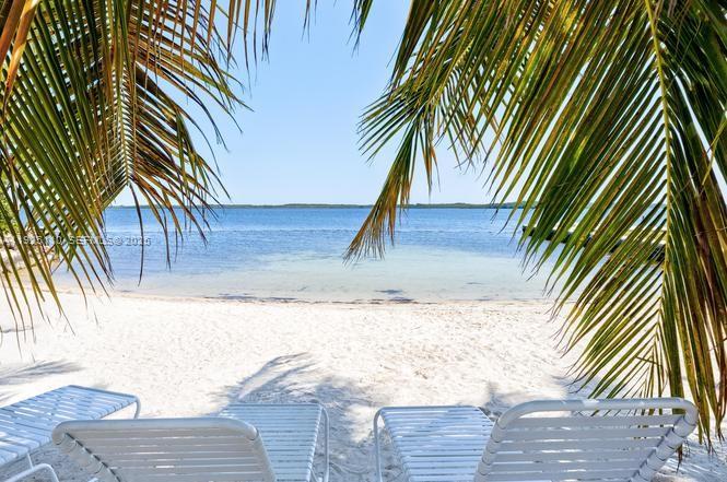 A sandy beach with lounge chairs framed by palm fronds overlooking the ocean — 29 Bonefish Ave, Key Largo FL 33037, KEY LARGO, FL