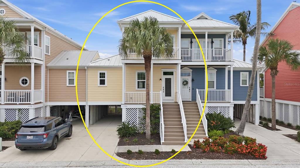 A yellow two-story coastal house with a front porch, stairs, and a palm tree — 11780 ANGLERS CLUB DRIVE UNIT 107, PLACIDA, FL