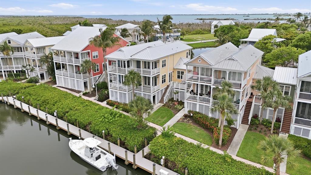 An aerial view shows several multi-story coastal houses with balconies along a canal with a boat — 11780 ANGLERS CLUB DRIVE UNIT 107, PLACIDA, FL