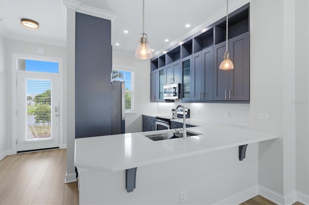 A kitchen features dark blue cabinets, white countertops, a sink, and two hanging pendant lights — 11780 ANGLERS CLUB DRIVE UNIT 107, PLACIDA, FL
