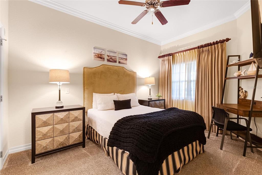 A bedroom features a queen bed, a wooden desk, a dresser, and a ceiling fan — 7656 WHISPER WAY UNIT 402, REUNION, FL