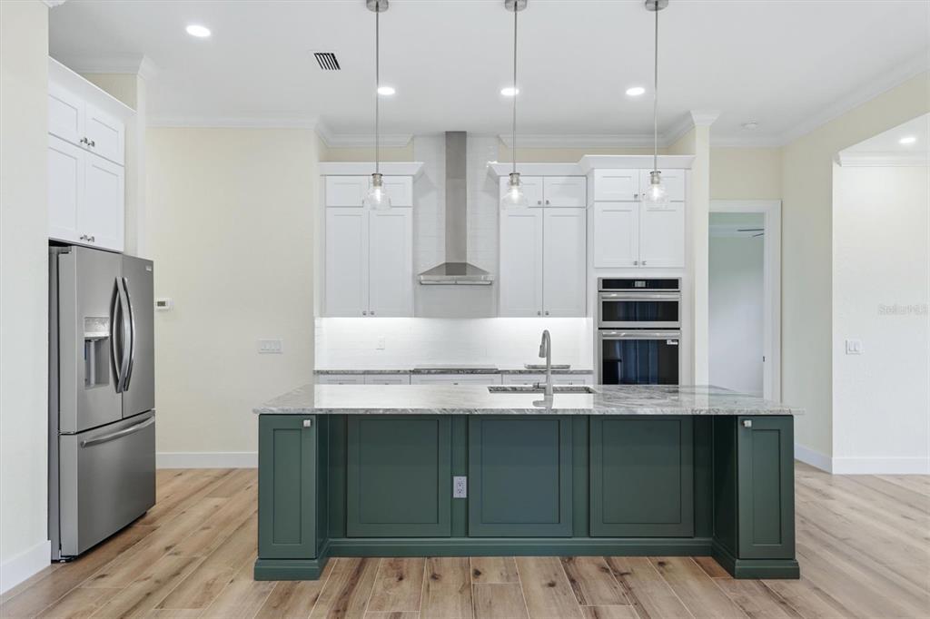 A kitchen features white upper cabinets, a dark green island, and stainless steel appliances — 2649 SIMONTON AVENUE, NORTH PORT, FL