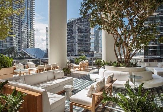 An outdoor terrace features white lounge seating, a large central tree, and surrounding city skyscrapers — 801 S Miami Ave # 3009, Miami FL 33130, MIAMI, FL