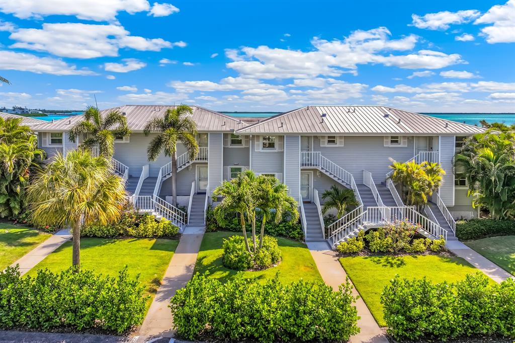 A two-story, light-gray residential building features exterior staircases, palm trees, and a grassy lawn — 5850 GASPARILLA ROAD UNIT M4, BOCA GRANDE, FL