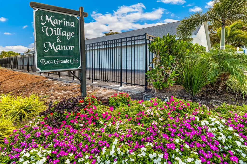 A sign for Marina Village & Manor stands before a fenced building and flower garden — 5850 GASPARILLA ROAD UNIT M4, BOCA GRANDE, FL