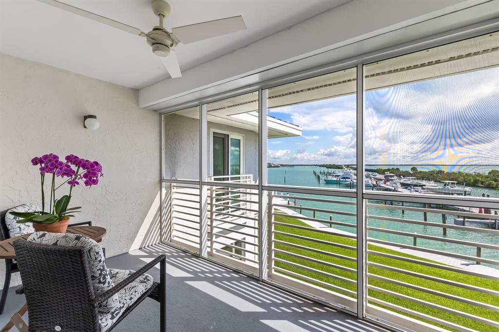 A screened-in balcony features a ceiling fan, wicker chairs, potted orchids, and a water view — 5850 GASPARILLA ROAD UNIT M4, BOCA GRANDE, FL