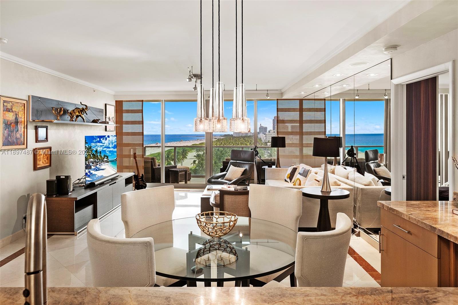 A dining area with a glass table overlooks a living room and ocean view — 1455 Ocean Dr # 1003, Miami Beach FL 33139, MIAMI BEACH, FL
