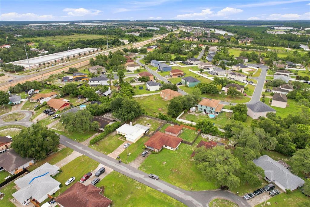 An aerial view shows a suburban neighborhood with houses, green lawns, and a nearby highway — 5055 CAMBRY LANE, LAKELAND, FL