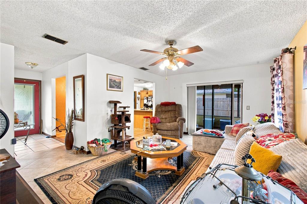 A living room features a ceiling fan, tiled floors, a rug, and a sliding glass door — 5055 CAMBRY LANE, LAKELAND, FL