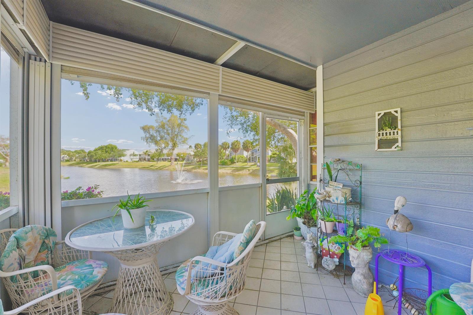 A screened-in porch features a glass-top table, wicker chairs, and a view of a lake — 5272 Buckhead Circle # 1010, Boca Raton FL 33486, BOCA RATON, FL