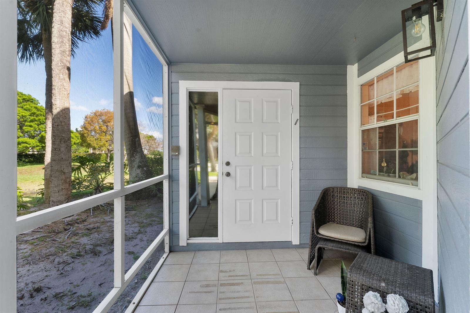 A screened-in porch features gray horizontal siding, a white front door, and tiled flooring — 5272 Buckhead Circle # 1010, Boca Raton FL 33486, BOCA RATON, FL