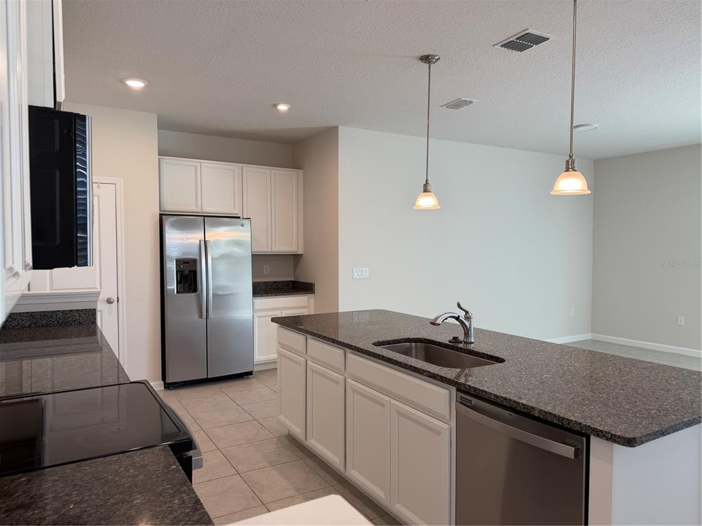 A kitchen features white cabinets, granite countertops, stainless steel appliances, and a central island — 2670 PLEASANT CYPRESS CIRCLE, KISSIMMEE, FL