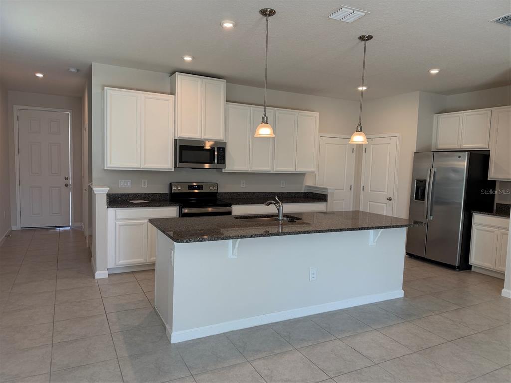 A kitchen with white cabinets, granite countertops, a center island, and stainless steel appliances — 2670 PLEASANT CYPRESS CIRCLE, KISSIMMEE, FL
