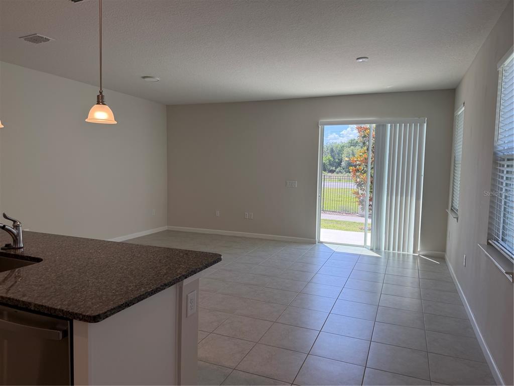 An open-concept living area features tile flooring, a kitchen island, and a sliding glass door — 2670 PLEASANT CYPRESS CIRCLE, KISSIMMEE, FL