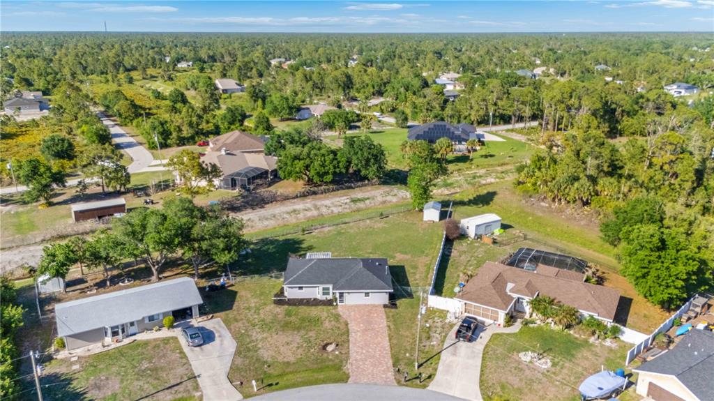 An aerial view shows several houses with driveways, lawns, and a small shed in a neighborhood — 7124 TOTEM AVENUE, NORTH PORT, FL