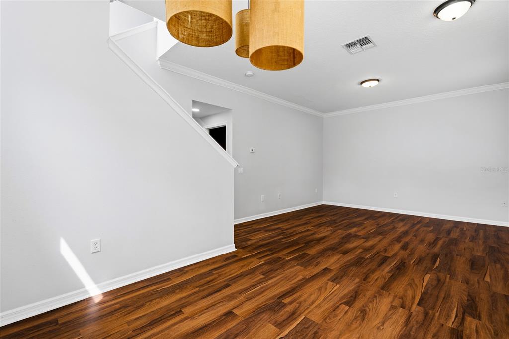An empty room with wood-look flooring, white walls, and three hanging cylindrical light fixtures — 6364 LAKE SMITH CIRCLE, WINDERMERE, FL