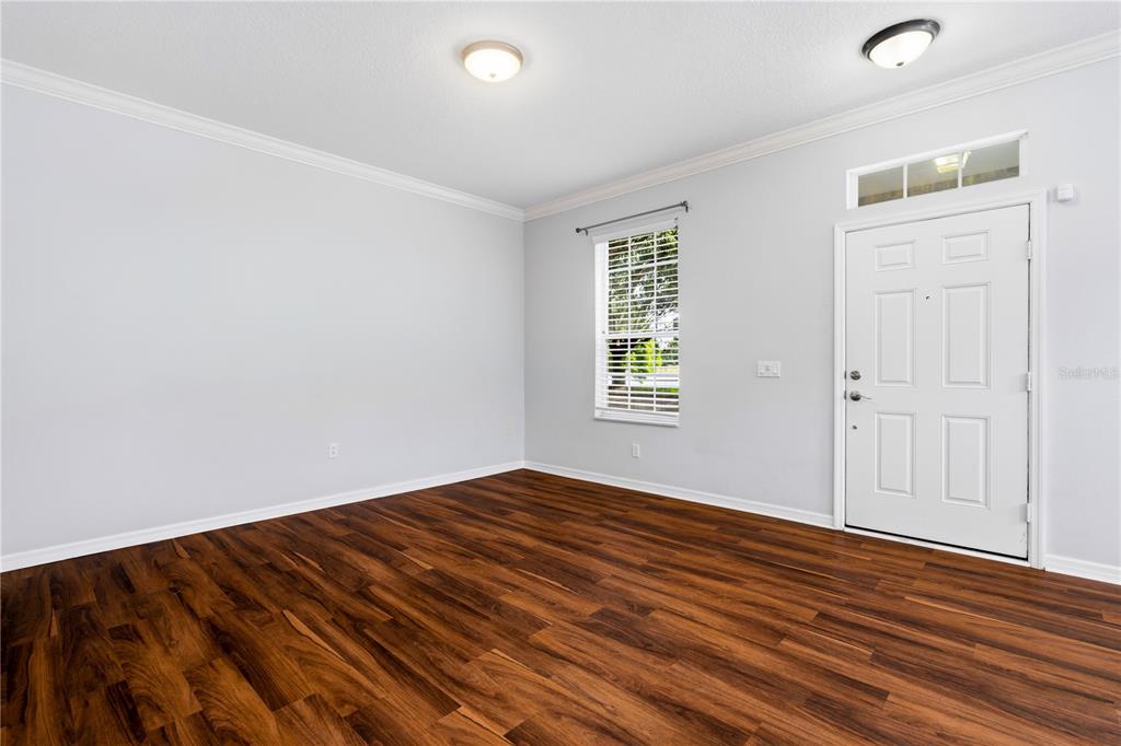 An empty room with light gray walls, dark wood-look flooring, a window, and a door — 6364 LAKE SMITH CIRCLE, WINDERMERE, FL